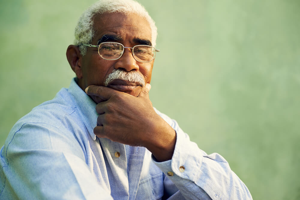 Older male wearing glasses with his hand on his chin