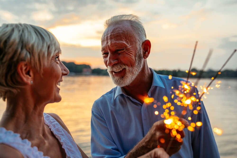 Mature couple on lake with sparklers