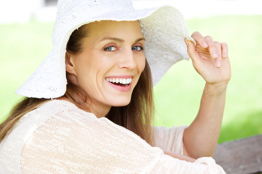 Older woman in floppy white hat smiling