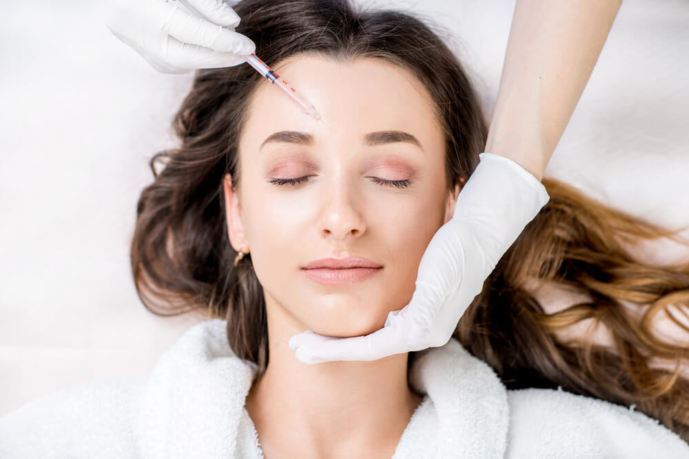 Young woman getting botox in forehead