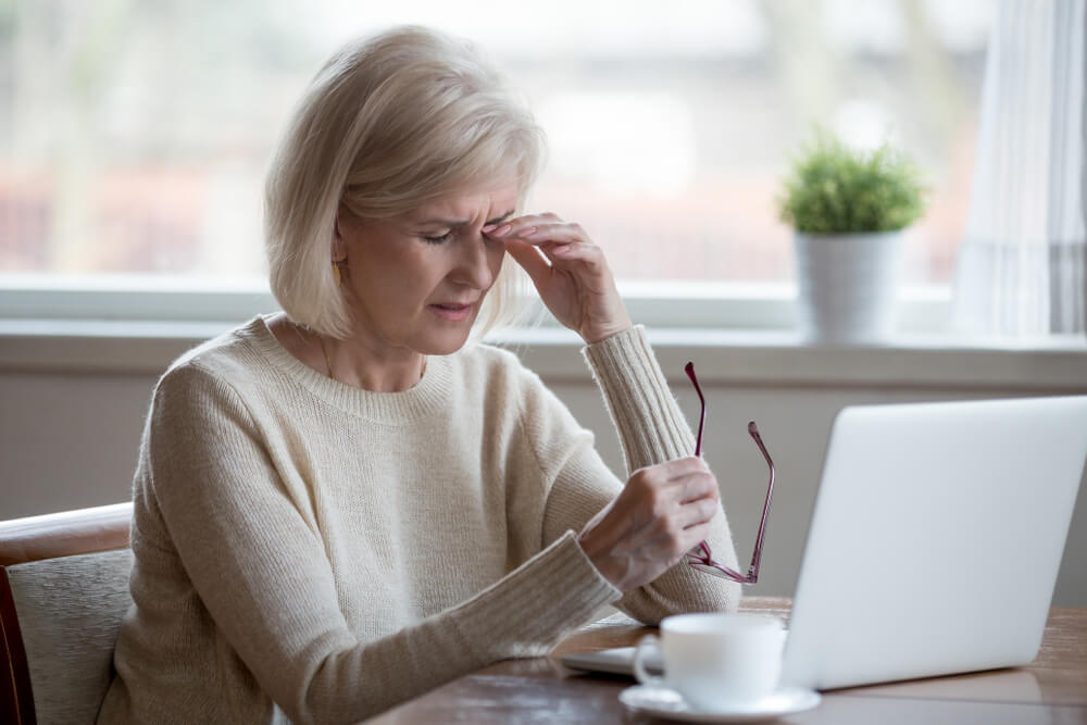 woman rubbing her eye after taking off her glasses