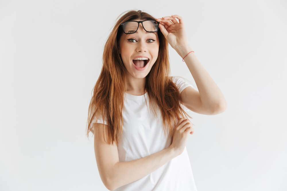 young woman looking surprised lifting up her glasses