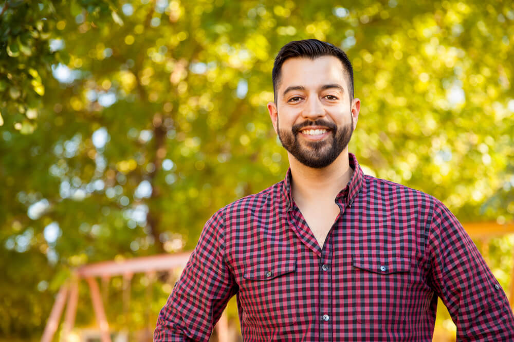 Young man in plaid shirt outdoors smiling